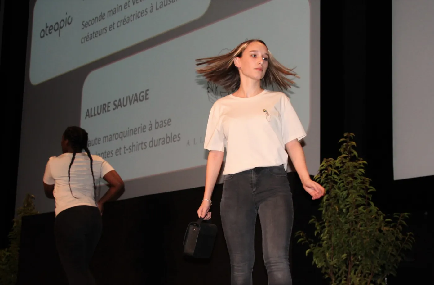 Une mannequin en t-shirt blanc devant l'écran qui présente Allure Sauvage