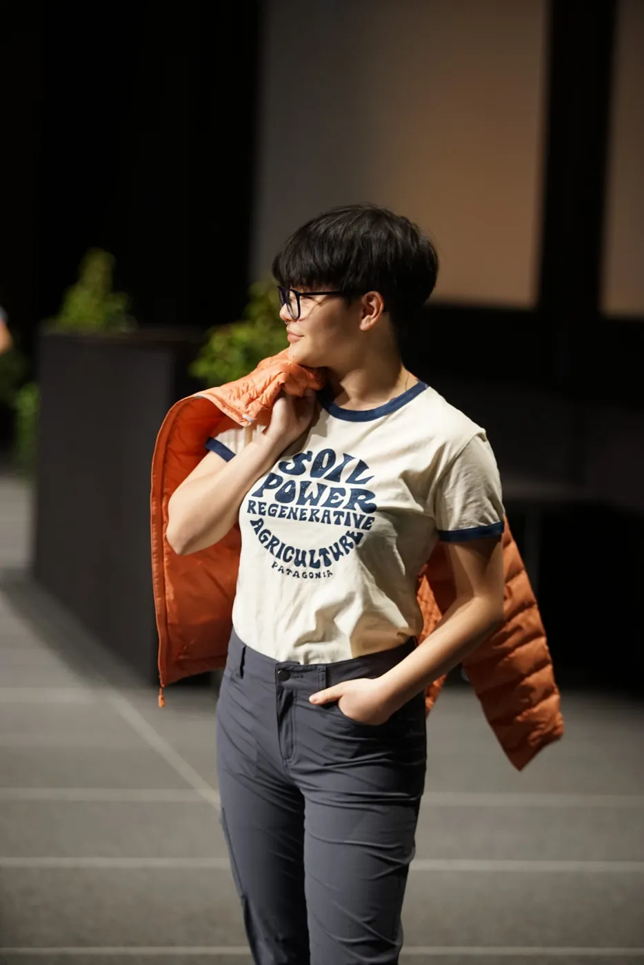 Un mannequin en t-shirt imprimé, une doudoune orange sur l'épaule