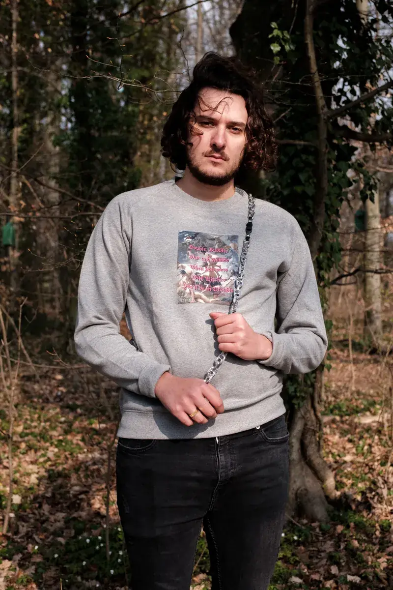 Un mannequin en sweat gris imprimé, entre les arbres