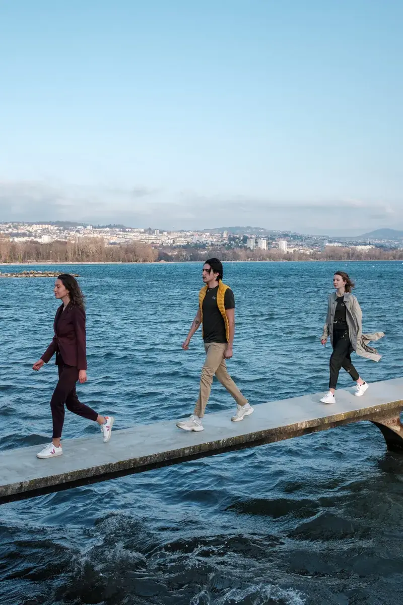 Trois mannequins marchent sur un ponton au-dessus du lac