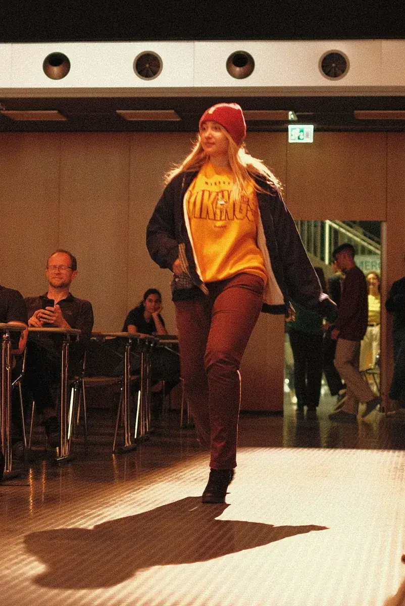 Nassima avance sur le podium en bonnet rouge, haut jaune et pantalon marron