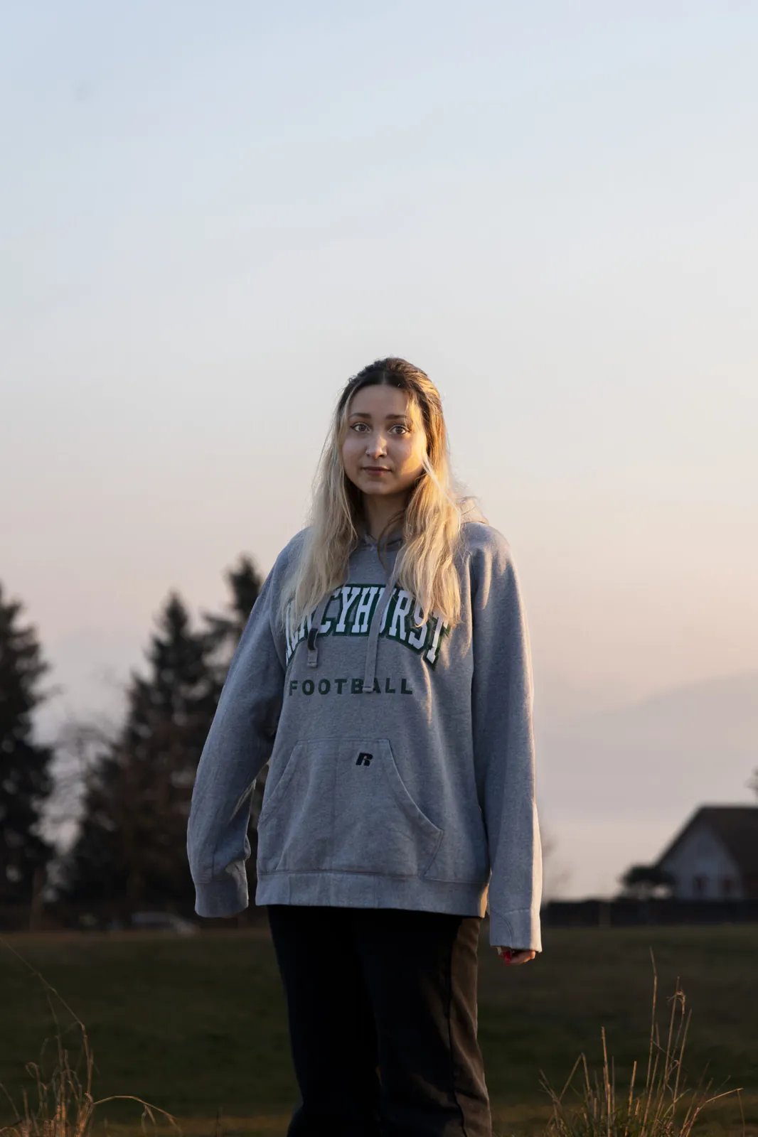 Une mannequin en sweat gris dans un champ, au crépuscule