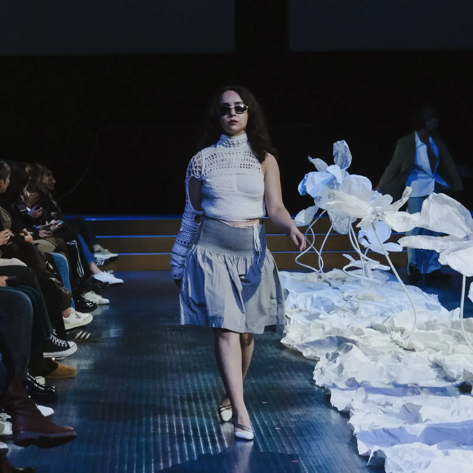 Une mannequin défile sur le podium de l'Ethical Fashion Show, entre des fleurs blanches