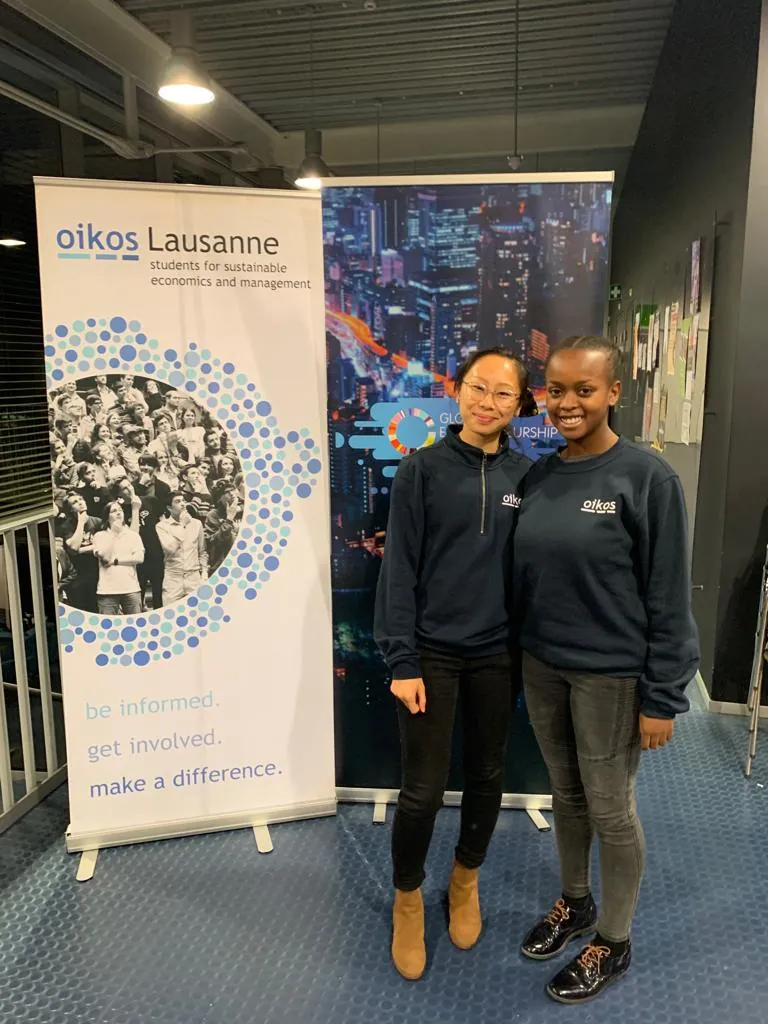 Deux membres d'oikos Lausanne en sweat oikos, entre le kakémono de l'association et celui de la Global Entrepreneurship Week